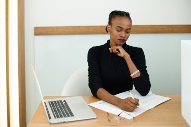 Zarif Afrikalı veya siyah Amerikalı kadın not defterinde el yazısı ile çene tutan