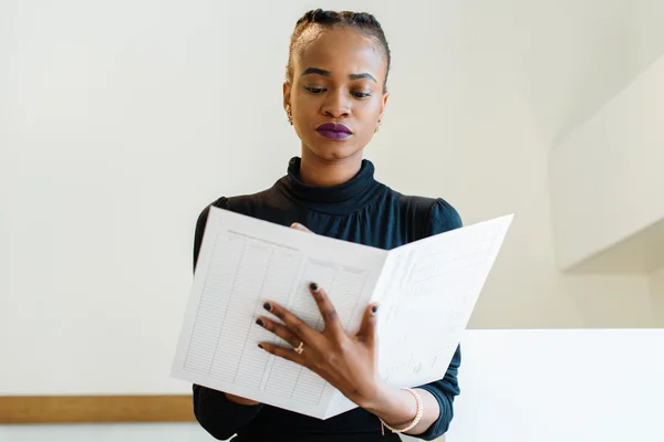 Primer plano de la exitosa mujer de negocios afroamericana o negra sosteniendo y mirando un archivo blanco grande —  Fotos de Stock