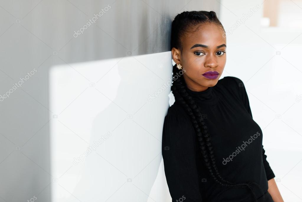 Side view of a serious african or black american woman looking at camera standing over white background