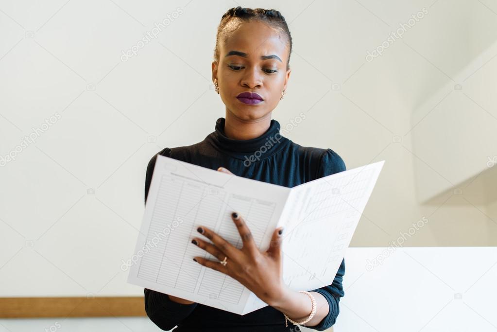 Close-up of successful African or black American business woman holding and looking at big white file
