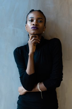 Zarif Afrika veya siyah Amerikalı kadın gri arka plan üzerinde çene altında el ile bakıyor