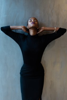 Tek zarif siyah kadın boyun elleriyle gri arka plan üzerinde tutan güzel koyu elbiseli