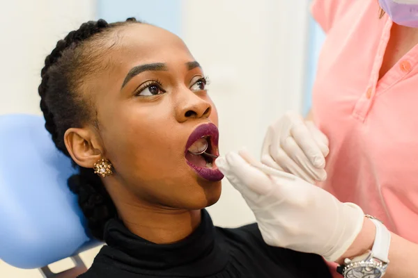 Молодая черная женщина с врачом-стоматологом во время обследования и лечения зубов — стоковое фото