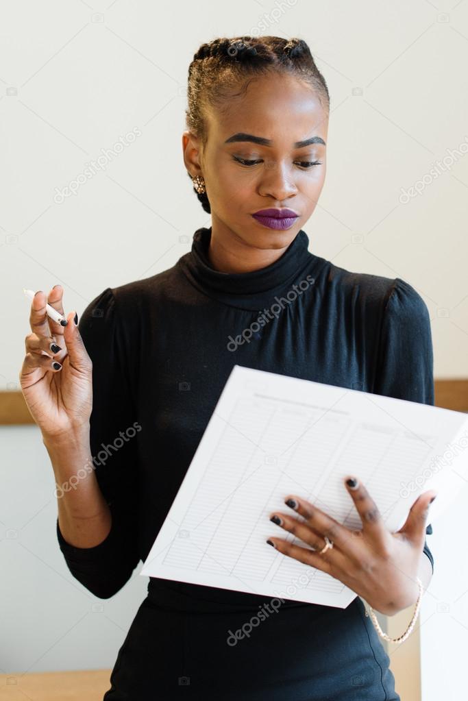 Close-up of confident elegant business woman wearing black dress in light office checking her agenda