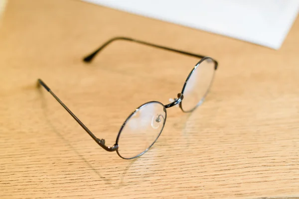 Óculos de plástico círculo preto na mesa de molho de madeira mínima — Fotografia de Stock