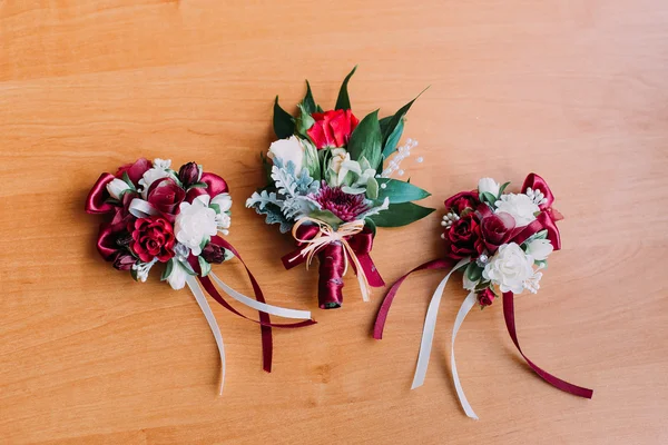 Três belas boutonnieres de flores vermelhas e brancas em fundo rústico de madeira — Fotografia de Stock