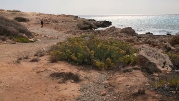 Μοναχικός άνθρωπος περπάτημα στην παραλία λιθοβολούνται σε μια όμορφη ηλιόλουστη μέρα. Κύπρος. — Αρχείο Βίντεο