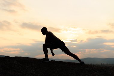 Güzellik ve spor kavram. Onun açık eğitim sırasında gün batımında poz vücut geliştirmeci silüeti