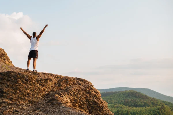 Zwarte gespierde atleet op de bergtop. Sport en vrijheid concept — Stockfoto