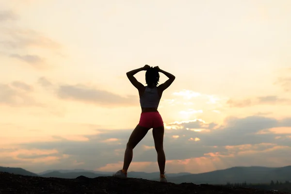 Σιλουέτα του ισχυρή και αυτοπεποίθηση μυϊκή γυναίκα που παρουσιάζουν στο ηλιοβασίλεμα — Φωτογραφία Αρχείου