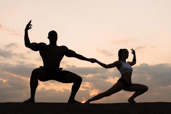 Σιλουέτες των μικτών ζευγάρι gymnasts χορό στο ηλιοβασίλεμα. Χάρη και την ομορφιά του σώματός τους ανθρώπους — Φωτογραφία Αρχείου