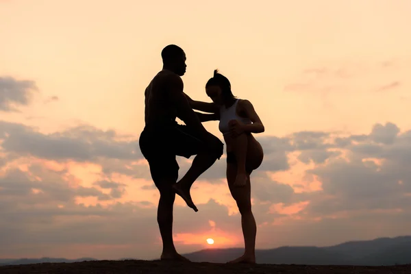 Silhouette di coppia gara mista in forma stretching e formazione insieme sullo sfondo delle montagne rocciose. Sport fitness concept — Foto Stock