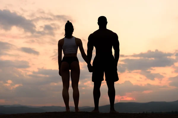 看日出的健身夫妇的身影。美丽和完美的人类的身体 — 图库照片