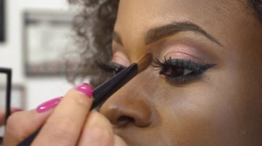 Siyah Afrika kökenli Amerikalı göz makyaj uygulamak makyaj sanatçısı modeli yakın çekim lashes. Güzellik ve moda kavramı