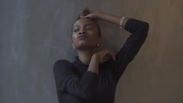Великолепная африканская американская модель позирует в элегантном черном вечернем платье на сером и серебряном фоне в студии . — стоковое видео