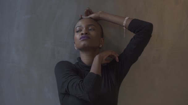 Wspaniały model african american pozowanie w elegancką czarną sukienkę na tle szary i srebrny w studio. — Wideo stockowe