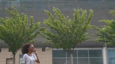 Beautiful young smiling african american business woman in sunglasses talking on cellphone while waiting for a flight at the airport.