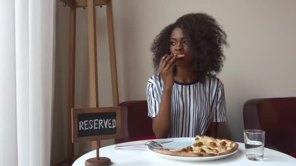 Mulher americana africana vegetariana elegante comendo pizza sem carne. Almoço de negócios no restaurante — Vídeo de Stock