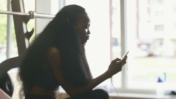 Krásná černoška s luxusní textilie dlouhé vlasy na její vnitřní smartphone — Stock video