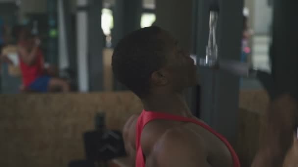 Vista lateral del entrenamiento del culturista negro en el aparato en la sala de gimnasio — Vídeos de Stock