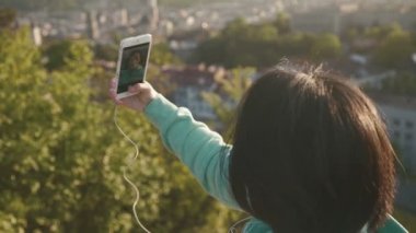 Güzel genç Japon kadın selfie açık telefonunu kullanarak ve gülümseyen parkta alarak
