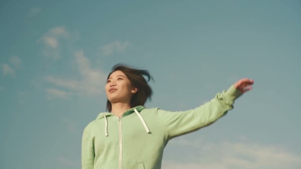 Sensual young asian woman with short hair stretching outdoor. Blue clean sky background — Stockvideo