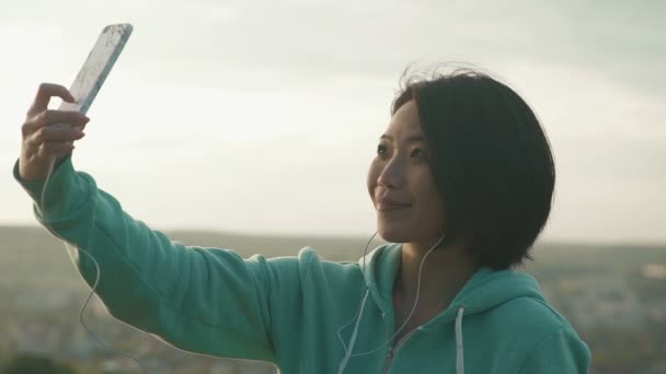 Mujer bastante japonesa tomando selfie al aire libre en el parque usando su teléfono y guiños — Vídeos de Stock