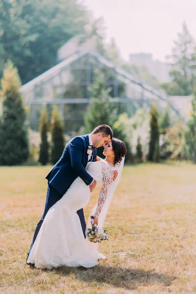 Güzel gelin muhteşem beyaz gelinlik ve şık mavi takım çim açık poz içinde damat ile. Arka plan, sera