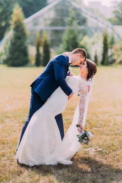 Güzel gelin beyaz gelinlik ve şık mavi takım çim açık poz içinde damat ile. Arka plan, sera