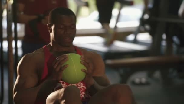 Cansado muscular sudoroso afroamericano hombre haciendo ejercicios con pelota en el gimnasio — Vídeos de Stock