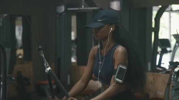 Sexy hermosa mujer afroamericana haciendo ejercicio en el gimnasio y escucha música en auriculares blancos — Vídeo de stock