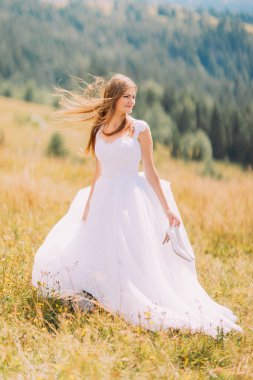 Güzel gelin altın sonbahar alanının arkasında şaşırtıcı dağ manzarası ile poz