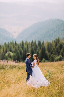 Güzel genç Düğün çifti birbirine arka plan olarak orman hills ile güneşli alan üzerinde tutan