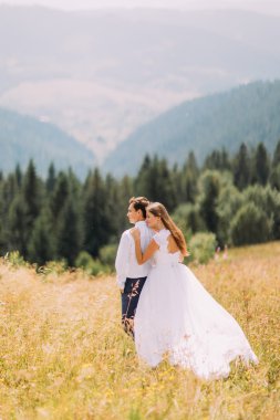 Güzel genç düğün çift arka plan olarak muhteşem orman hills ile güneşli alan üzerinde