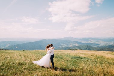 Genç evlilik çift rüzgarlı güneşli alan arka plan olarak uzak orman hills ile poz