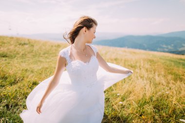 Romantik gelin altın sonbahar alanında küçük çiçekli beyaz elbise poz. Hill manzara arka plan