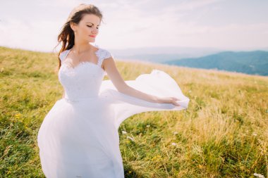 Romantik gelin sarı-yeşil alan küçük çiçekler ile poz. Hill manzara arka plan