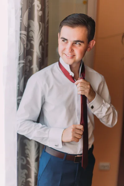 Joven hombre guapo vistiendo corbata moderna en la habitación de hotel — Foto de Stock