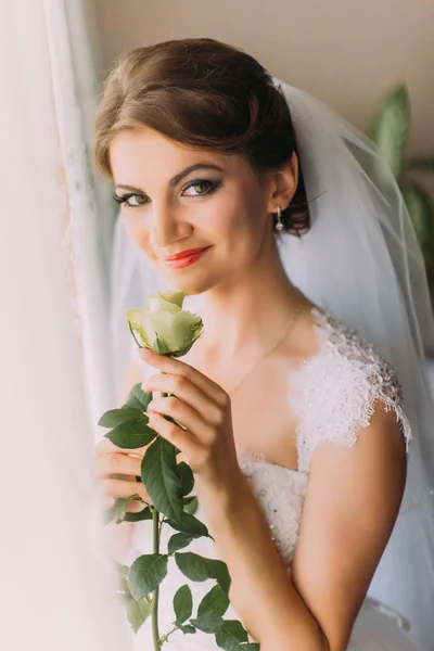 Delicata rosa nelle mani della giovane sposa vestita abito bianco — Foto Stock