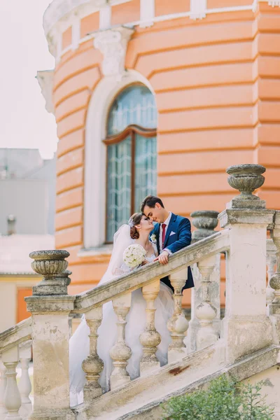 Casal jovem elegante bonito em escadas no parque. Palácio antigo romântico no fundo — Fotografia de Stock