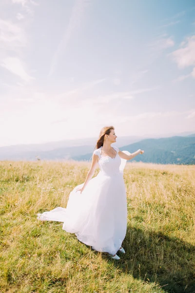 Noiva posando no campo de outono dourado com uma bela paisagem colina atrás dela — Fotografia de Stock