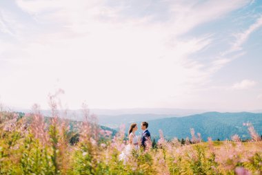 İki aşıklar-beyaz elbise ve onu yakışıklı adam genç güzel kız, çayır vurdu. Ön planda alan çiçekleri