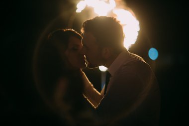 Önünde yanan kalp yeni evli çift romantik ve duygusal öpücük. Lens parlaması ile gece çekimi