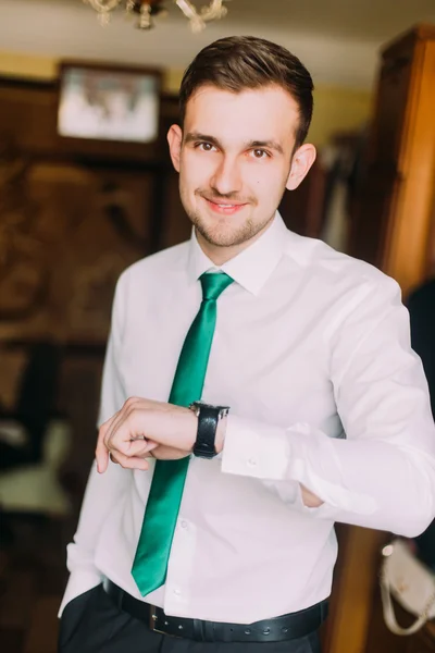 Jonge knappe zakenman in wit shirt met groene stropdas controleren tijd kijken op zijn horloge — Stockfoto