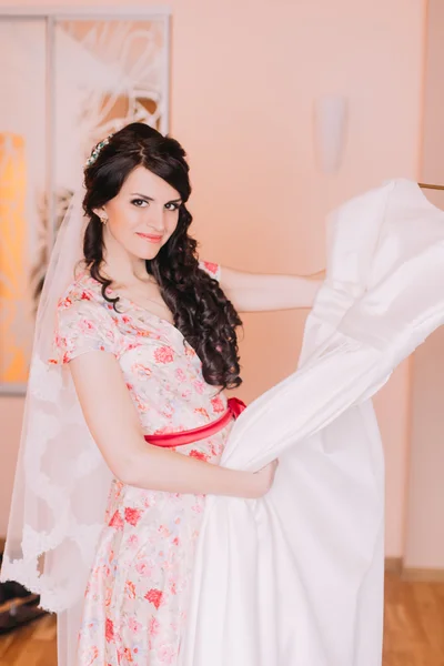 Menina bonita segurando vestido de casamento no camarim, preparando-se para vesti-lo para seu casamento — Fotografia de Stock