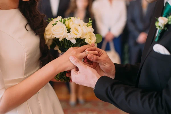Stijlvolle bruidegom zetten ring op vinger van zijn elegante bruid op huwelijksceremonie — Stockfoto