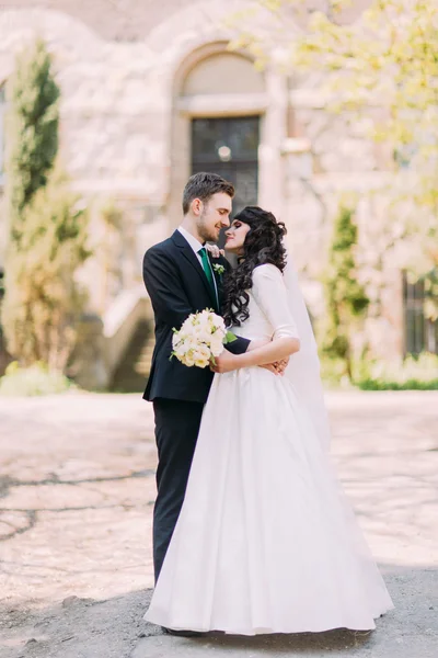 Sevgi dolu çift portresi. Güzel gelin ve yakışıklı damat parkta poz. Arka planda eski vintage bina