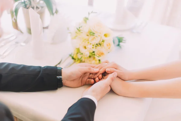 Закройте мужские и женские руки над белым столом с цветочным букетом. — стоковое фото