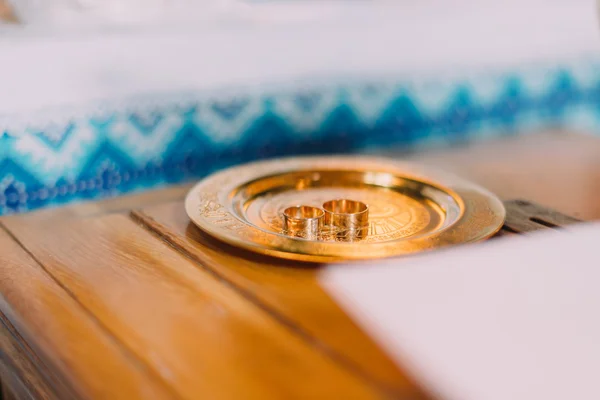 Par de anillos de boda en un salver de oro con tela tradicional eslava ornamentada en el fondo —  Fotos de Stock
