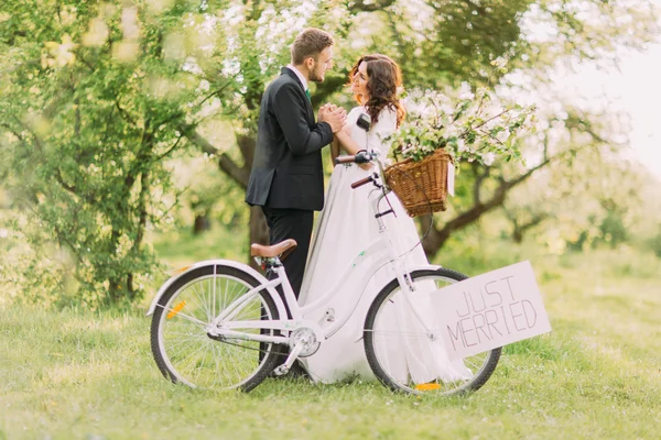 Sensual romántico joven recién casada pareja posando en el parque con la bicicleta — Foto de Stock